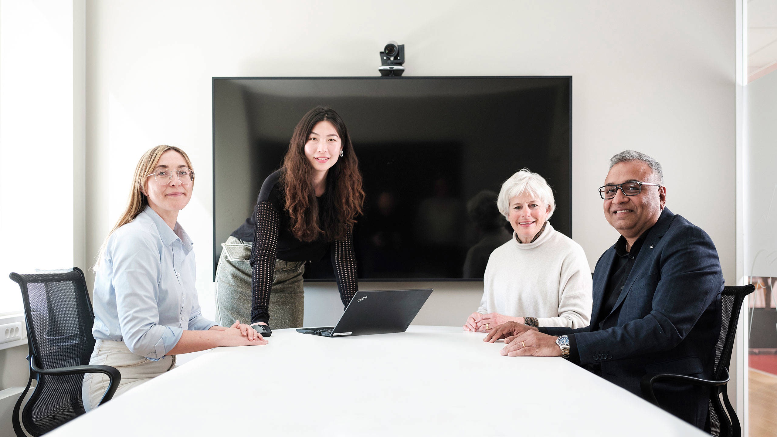 Four people in a meeting room facing the camera